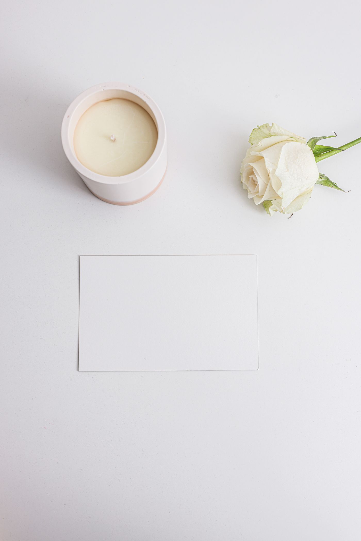 Blank remembrance card beside a white rose and candle